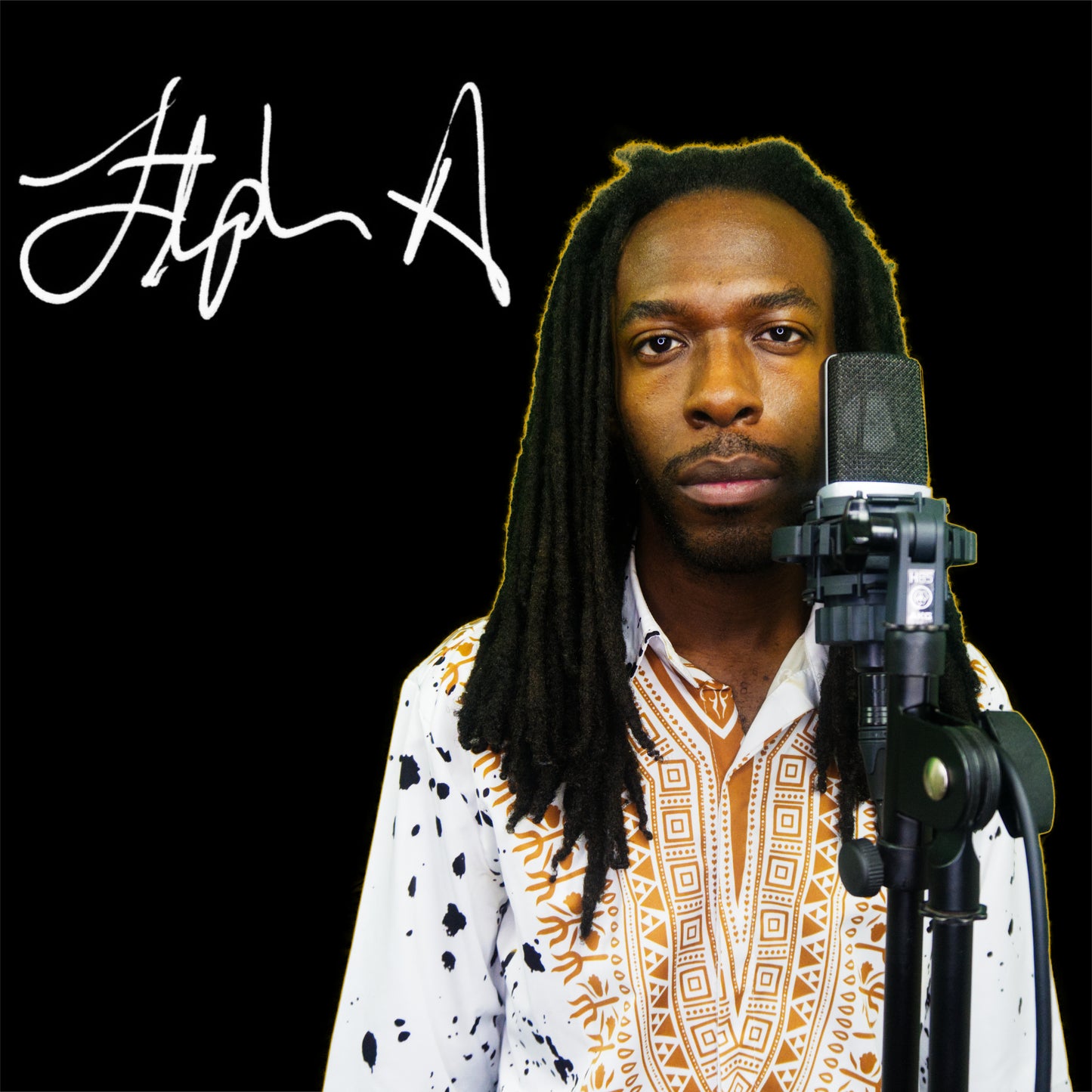 A man with a microphone stands in front of a dark background with a sheet of music or lyrics in front of him. His shirt is white with a paint splatter design and he has a reggae-style haircut. Stephen Allen Music