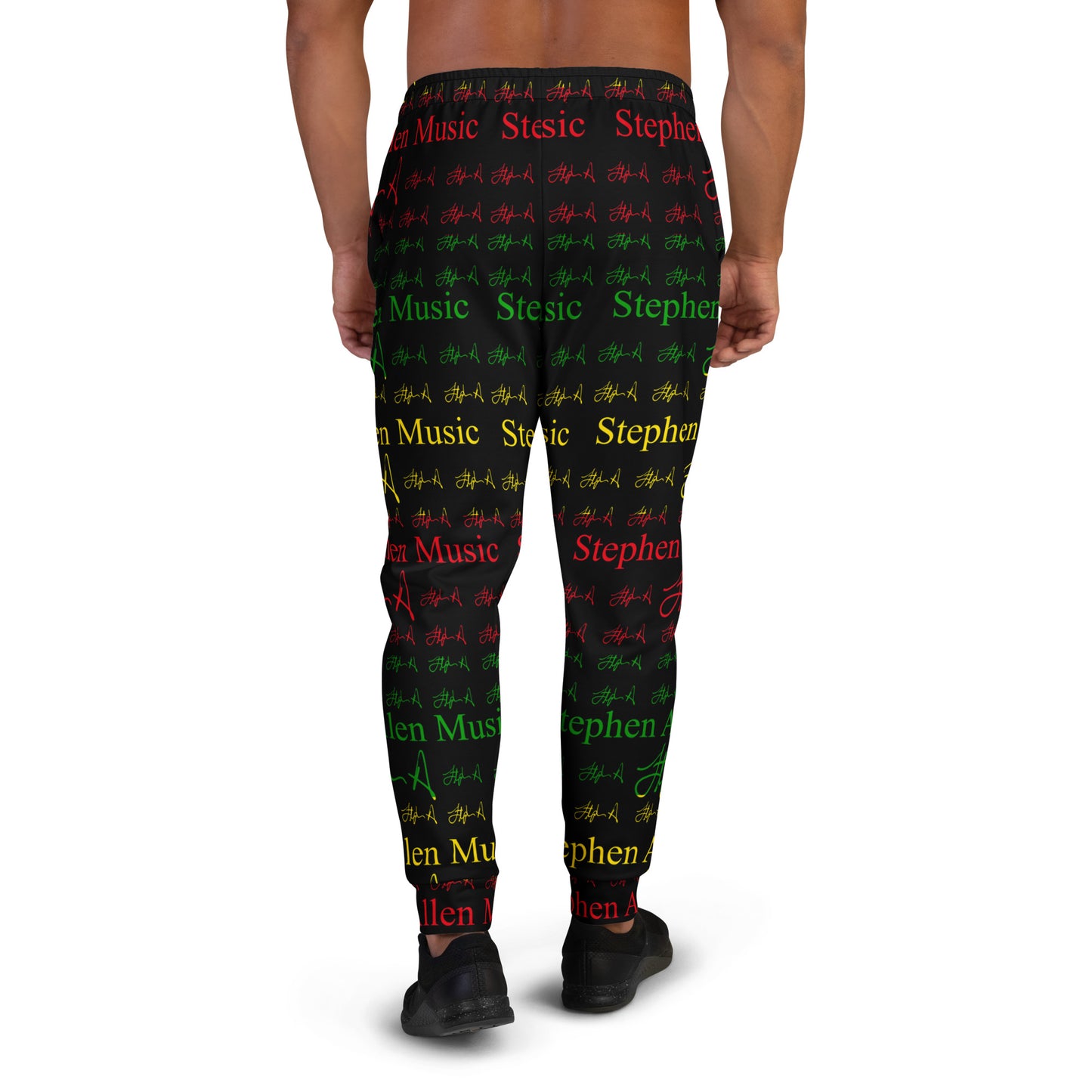 A person modeling black jogger-style pants with an allover repeating pattern of red, green, and yellow text and symbols on a white studio background. Stephen Allen Music
