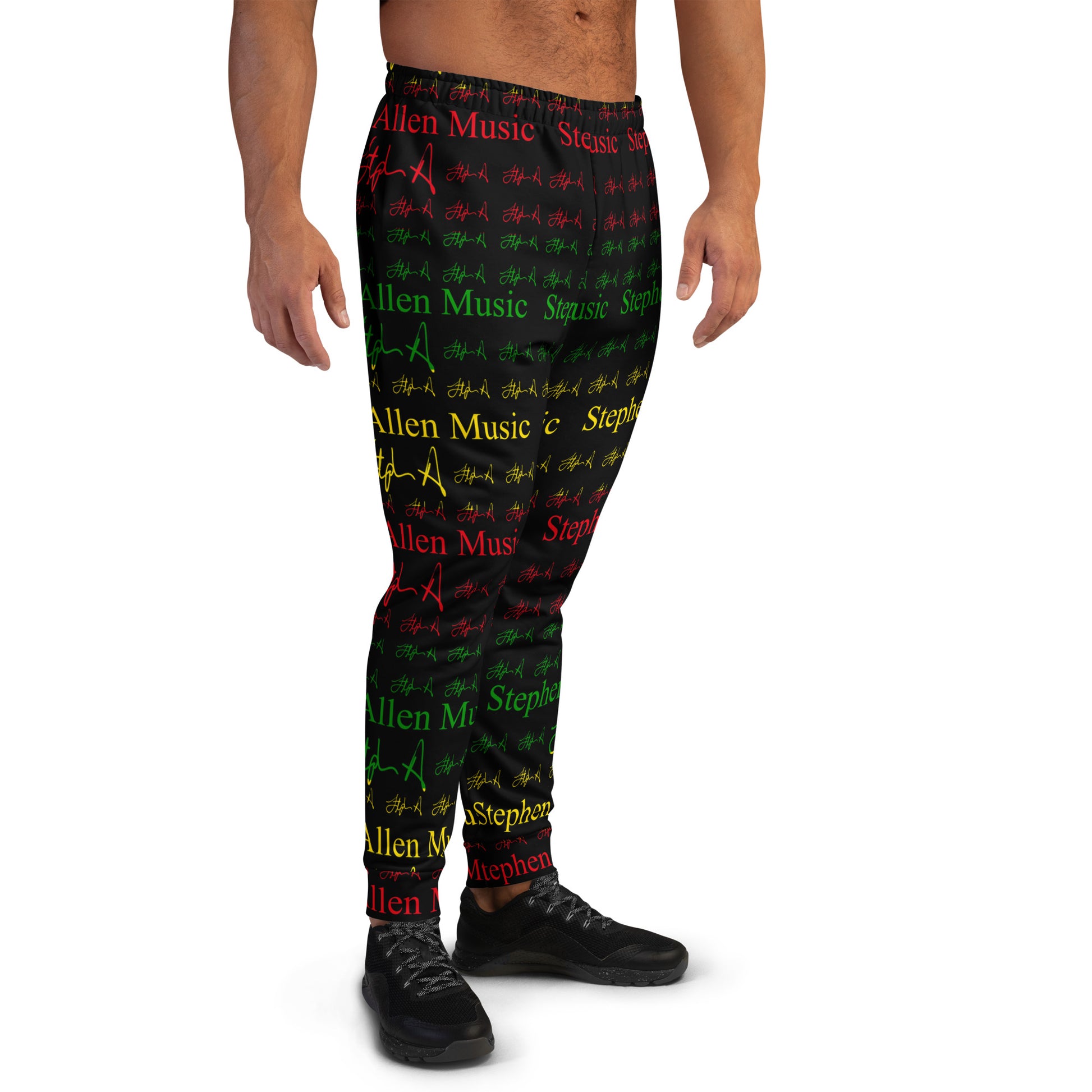 A person modeling black jogger-style pants with an allover repeating pattern of red, green, and yellow text and symbols on a white studio background. Stephen Allen Music