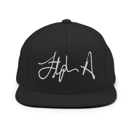 A black flat-brim baseball cap featuring a stylized embroidered signature logo in white thread on the front panel, set against a plain white background. Stephen Allen Music